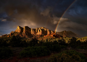 Скалы на фоне неба с радугой над ними.